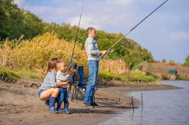 A happy family spends time together; they teach their son to fish.