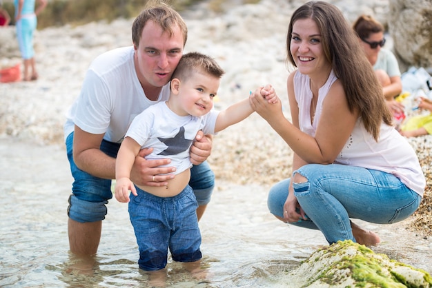 Photo happy family standing on a wood pontoon in front of the sea in summertime