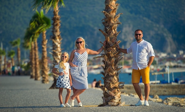 A happy family stands under a palm tree on the waterfront in Fethiye. Turkey.