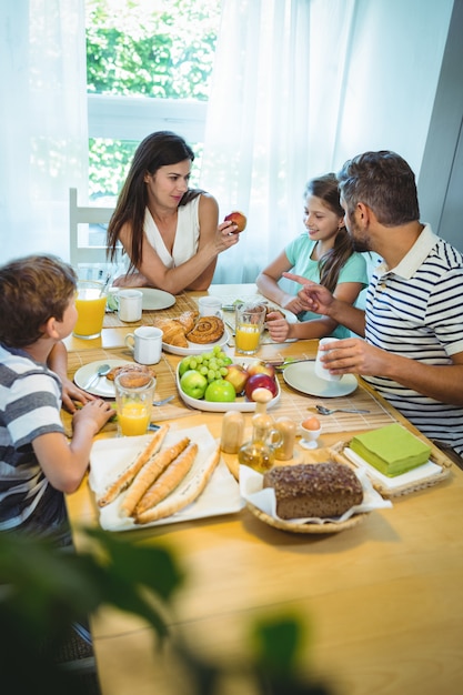 Happy family talking to each other while having breakfast together