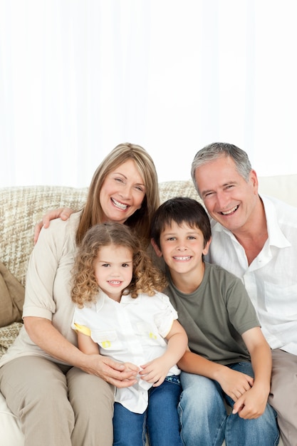 A happy family on their sofa looking at the camera 