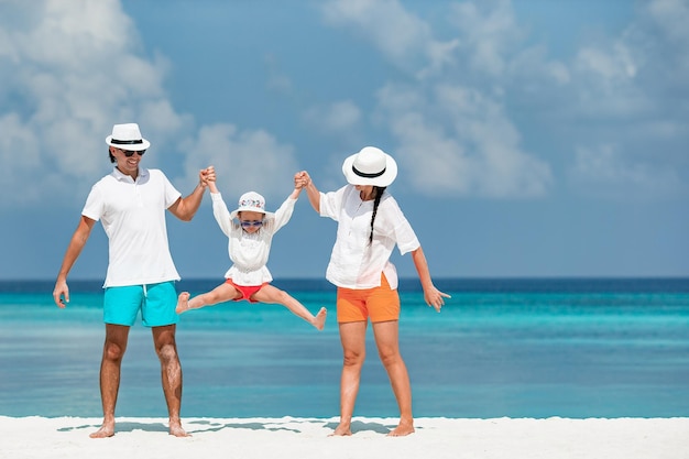 Felice famiglia di tre persone che si divertono insieme sulla spiaggia