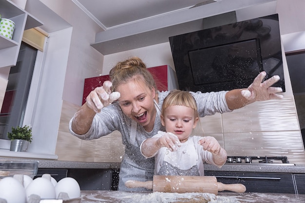 Foto famiglia felice una figlia minuscola trascorre del tempo con sua madre in cucina a cuocere i biscotti