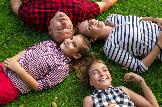 Happy family together laying on green grass.Beautiful day together in park