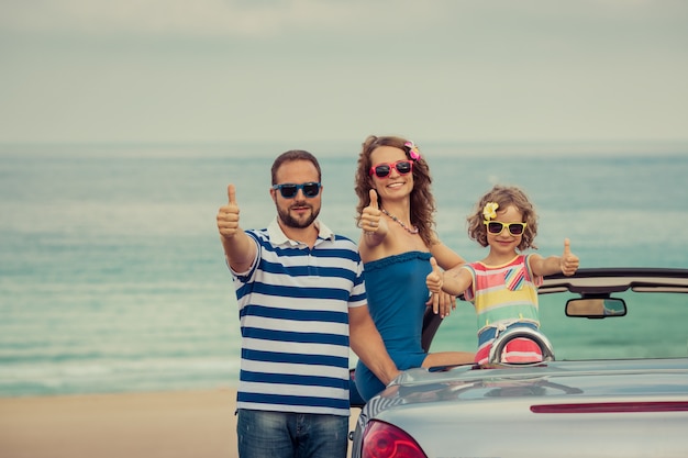Happy family travel by car to the sea people having fun in\
cabriolet summer vacation concept
