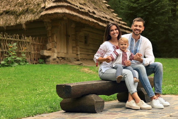 Счастливая семья в украинской национальной одежде сидит на скамейке под открытым небом