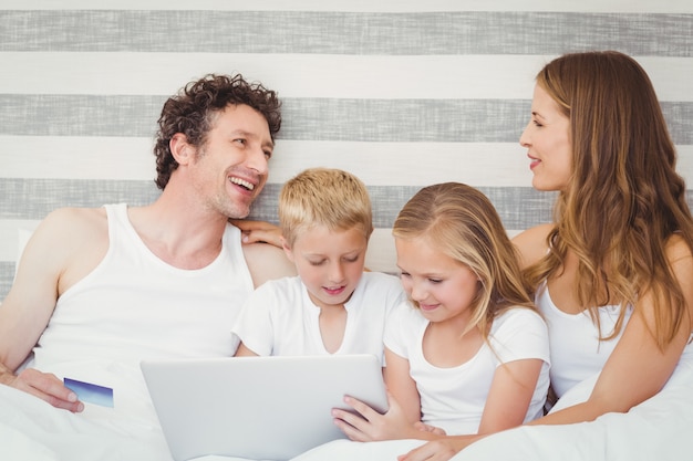 Happy family using laptop on bed