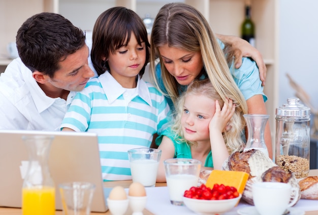 Famiglia felice con laptop durante la colazione