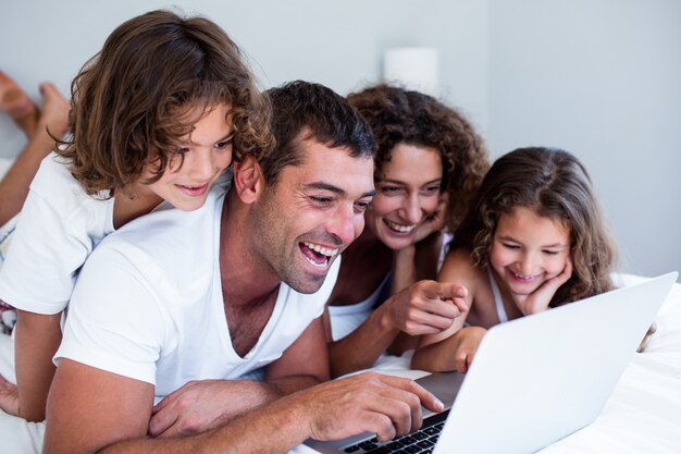 Happy family using laptop together on bed