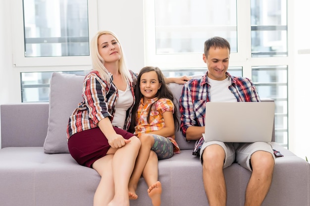 Счастливая семья вместе с ноутбуком на диване в доме