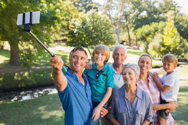 Famiglia felice che utilizza un bastone del selfie nel parco