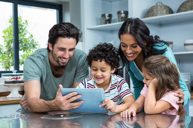 Photo happy family using tablet in kitchen