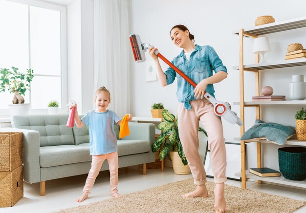 Happy family vacuuming the room. Mother and daughter doing the cleaning in the house.