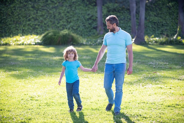 幸せな家族の価値。子供の頃と親。親は草の上で小さな子供男の子を導きます。夏の日に子供男の子とお父さん。子育てと父性。父の日。父と息子は公園を散歩します。