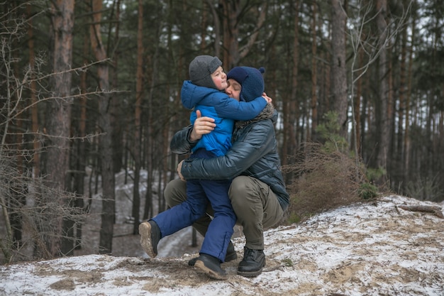 Happy family on a walk outdoors in sunny winter forest, Christmas holidays, father and son play together