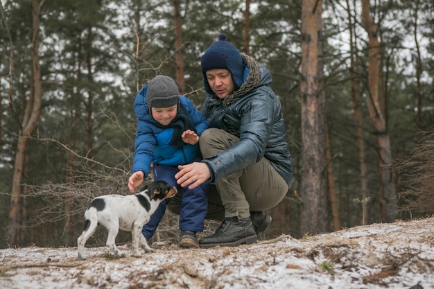 日当たりの良い冬の森、クリスマス休暇、父と息子が一緒に遊ぶ屋外散歩で幸せな家族