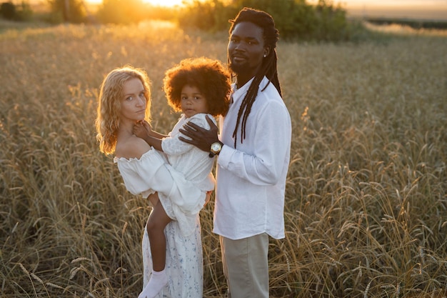 Foto famiglia felice in una passeggiata in un campo estivo al tramonto