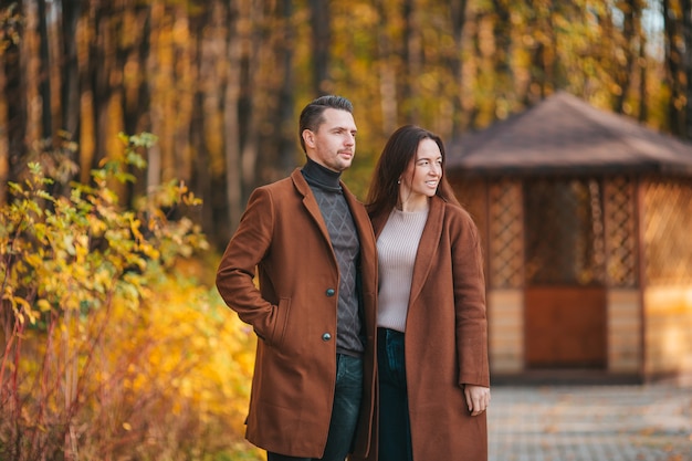 Famiglia felice che cammina nella sosta di autunno sulla giornata di sole autunnale