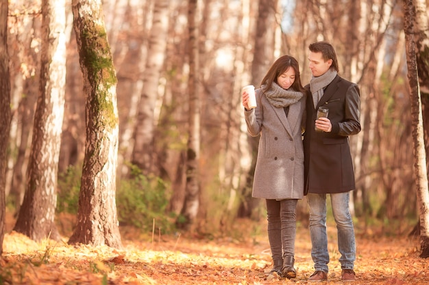 Happy family walking in autumn park on sunny fall day