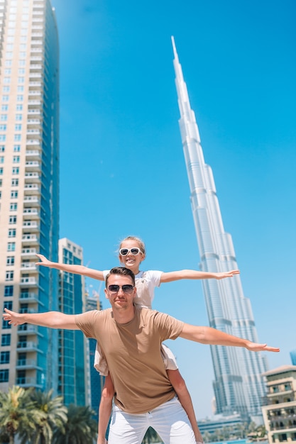 Happy family walking in Dubai with Burj Khalifa skyscraper in the background.