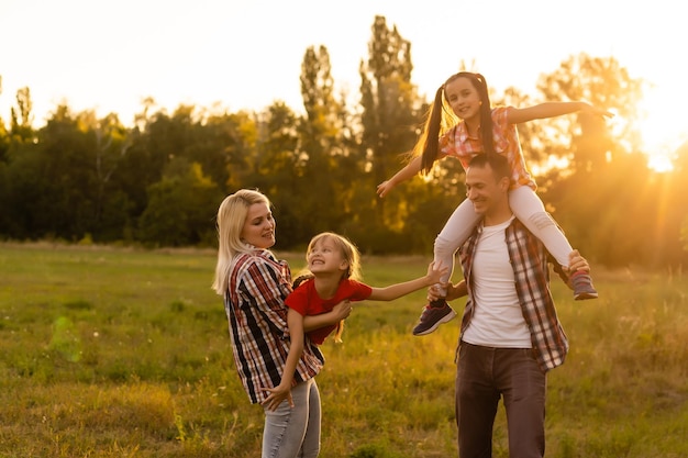 Famiglia felice che cammina nel campo e guarda il tramonto