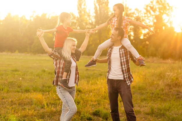 Famiglia felice che cammina nel campo e guarda il tramonto