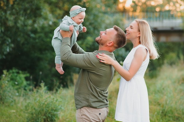 Happy family walking on field in nature at sunset