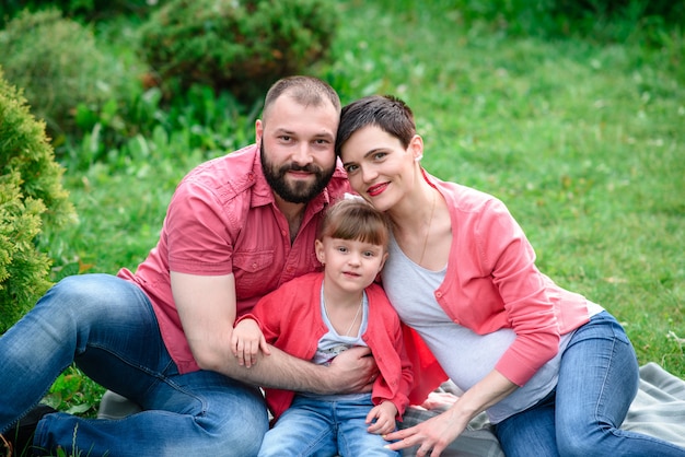 Foto famiglia felice che cammina nel parco. gravidanza.