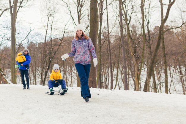 Happy family walking in winter park together, two adult man and woman and two children