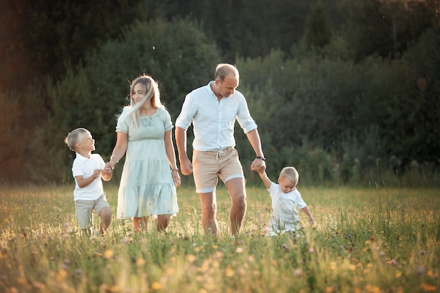 Photo happy family walks in the field in summer fun at sunset