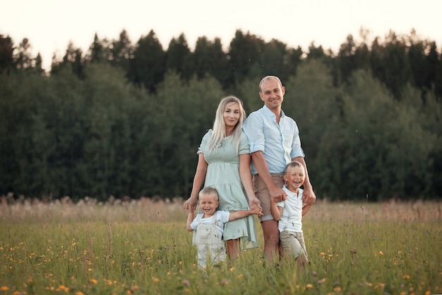 Happy family walks in the field in summer fun at sunset