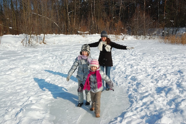 Happy family walks in winter, having fun and playing with snow outdoors on holiday weekend