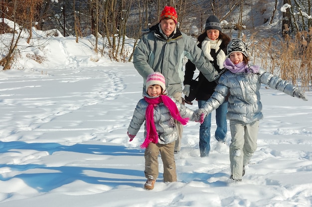 Happy family walks in winter, having fun and playing with snow outdoors on holiday weekend