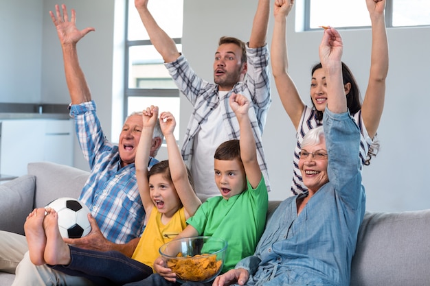 Happy family watching a football match at home