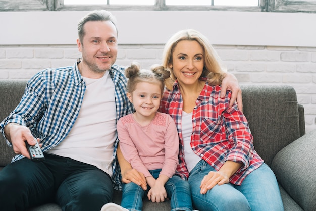 Photo happy family watching television together on sofa