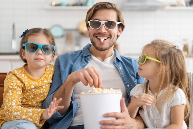 Happy family watching TV at home and eating popcorn.