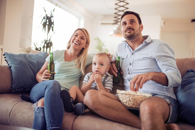 Happy family watching TV on sofa at home