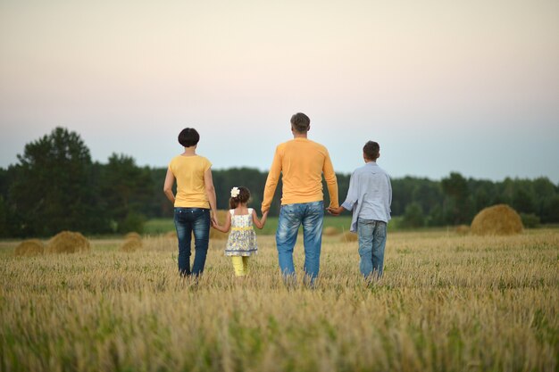 Happy family in wheat field in sunny day,back view