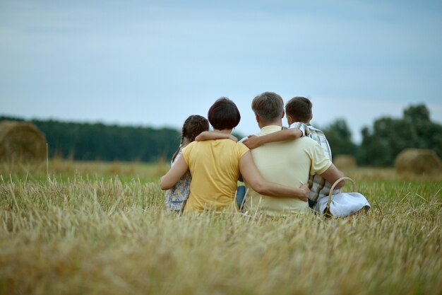 Happy family in wheat field in sunny day,back view