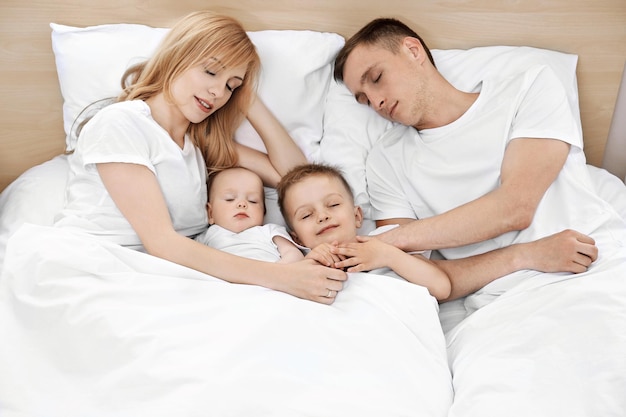 Happy family on white bed in bedroom