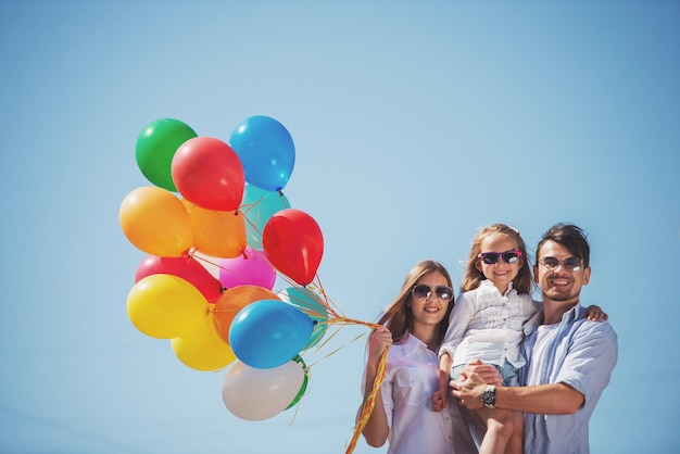 Счастливая семья с воздушными шарами на открытом воздухе в летний день. Фон неба.