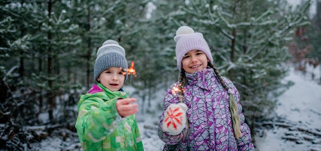 Happy family with burning sparklers during walking in forest on snowing day christmas celebration