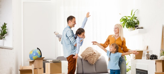 Happy family with cardboard boxes in new house at moving day.