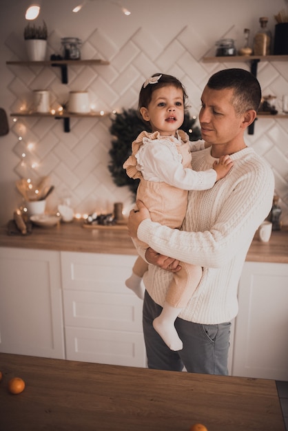 Happy family with child celebrating New Year and Christmas at decorated Christmas tree and garlan