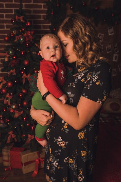 Happy family with child celebrating New Year and Christmas at decorated Christmas tree and garlands