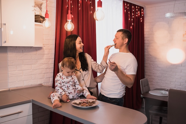 Happy family with child celebrating New Year and Christmas at decorated Christmas tree and garlands