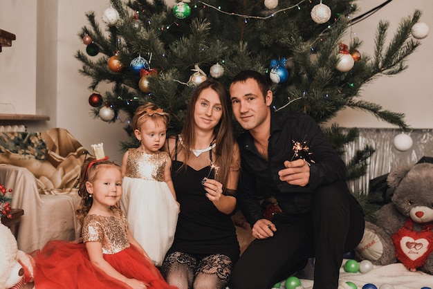 Happy family with child celebrating New Year and Christmas at decorated Christmas tree and garlands