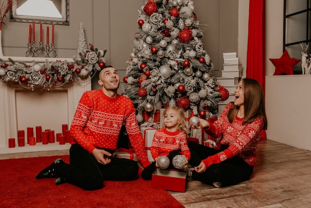 Happy family with child celebrating New Year and Christmas at decorated Christmas tree and garlands