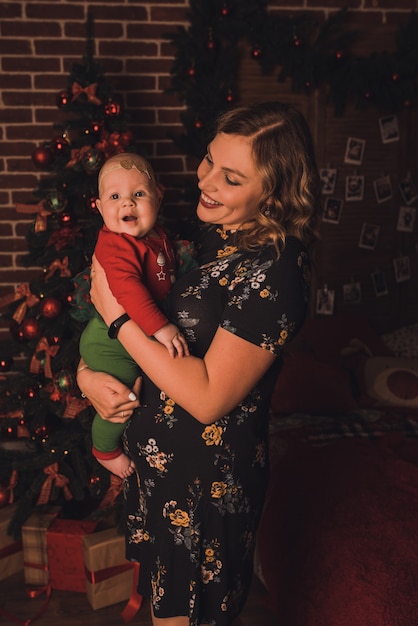 Foto famiglia felice con bambino che celebra il nuovo anno e il natale all'albero di natale decorato e alle ghirlande