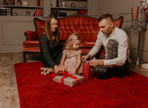 Famiglia felice con bambino che celebra il nuovo anno e il natale all'albero di natale decorato e alle ghirlande